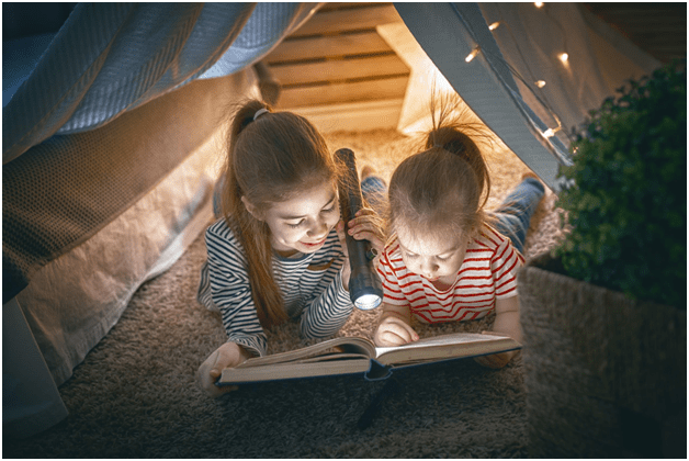 children reading a book in a tent