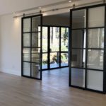 Empty living quarters with double suspended black frame glass barn door