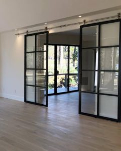 Empty living quarters with double suspended black frame glass barn door